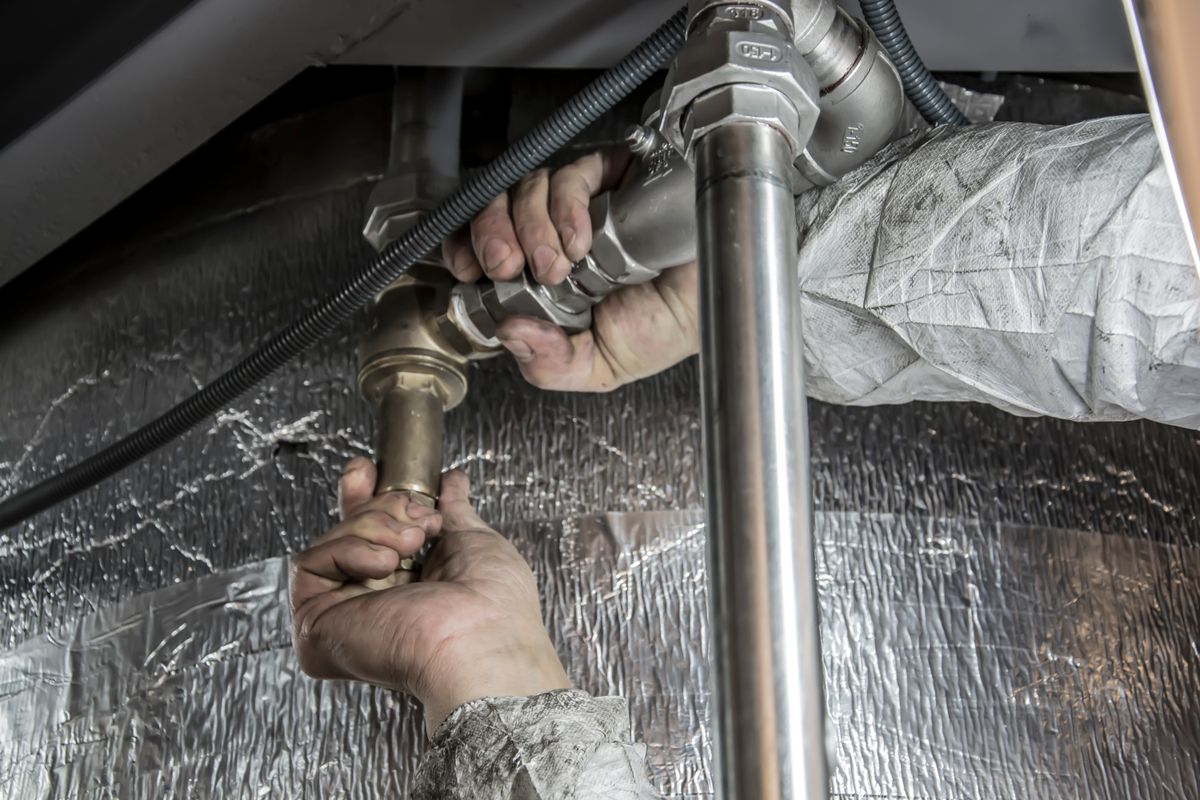 A worker fitting steel pipes during an indoor plumbing repair