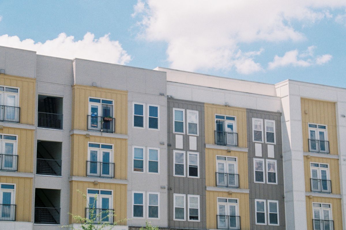 A modern apartment building exterior, the kind an absentee owner rarely sees in person.