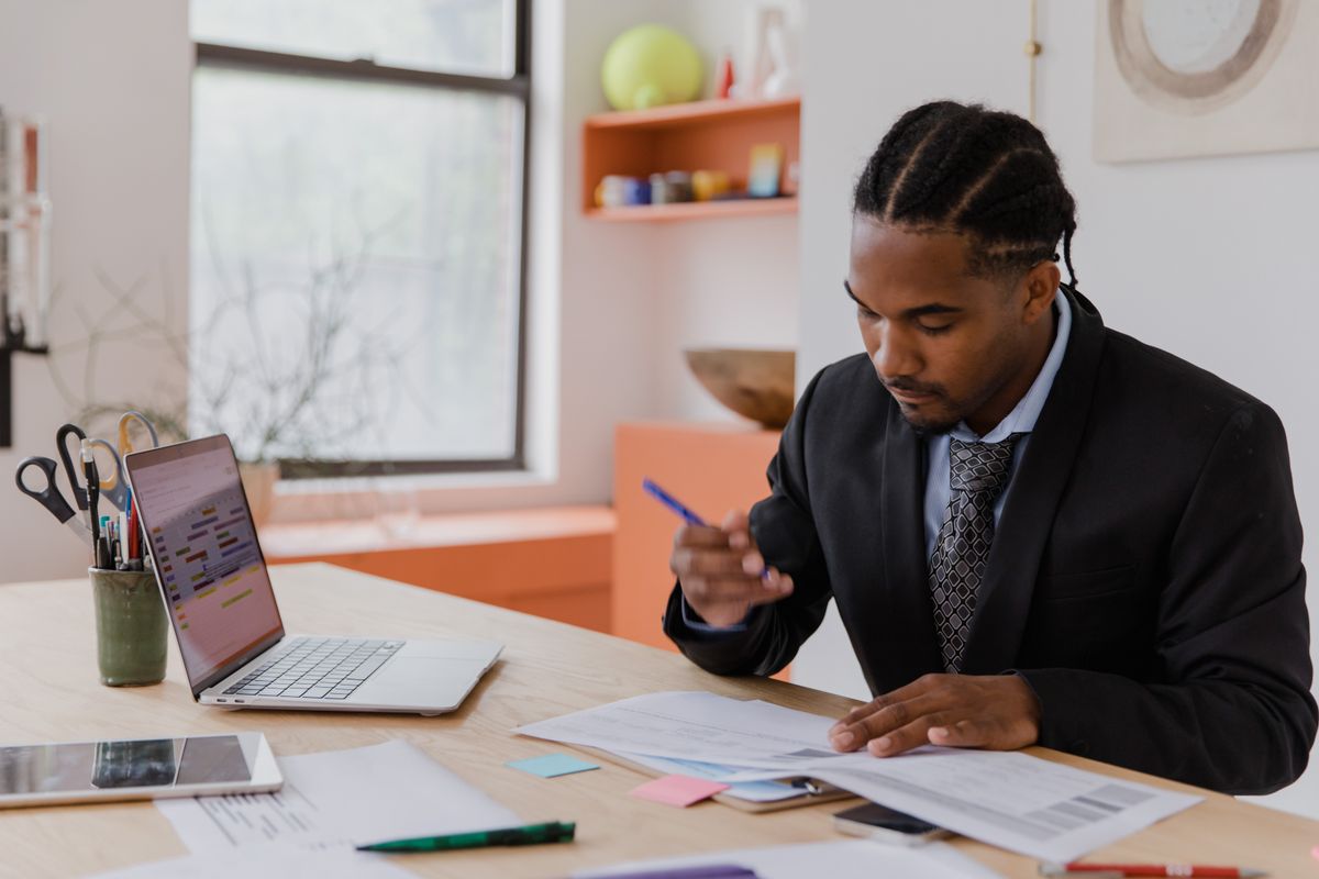 A property owner at a desk reviewing printed statements alongside a laptop.