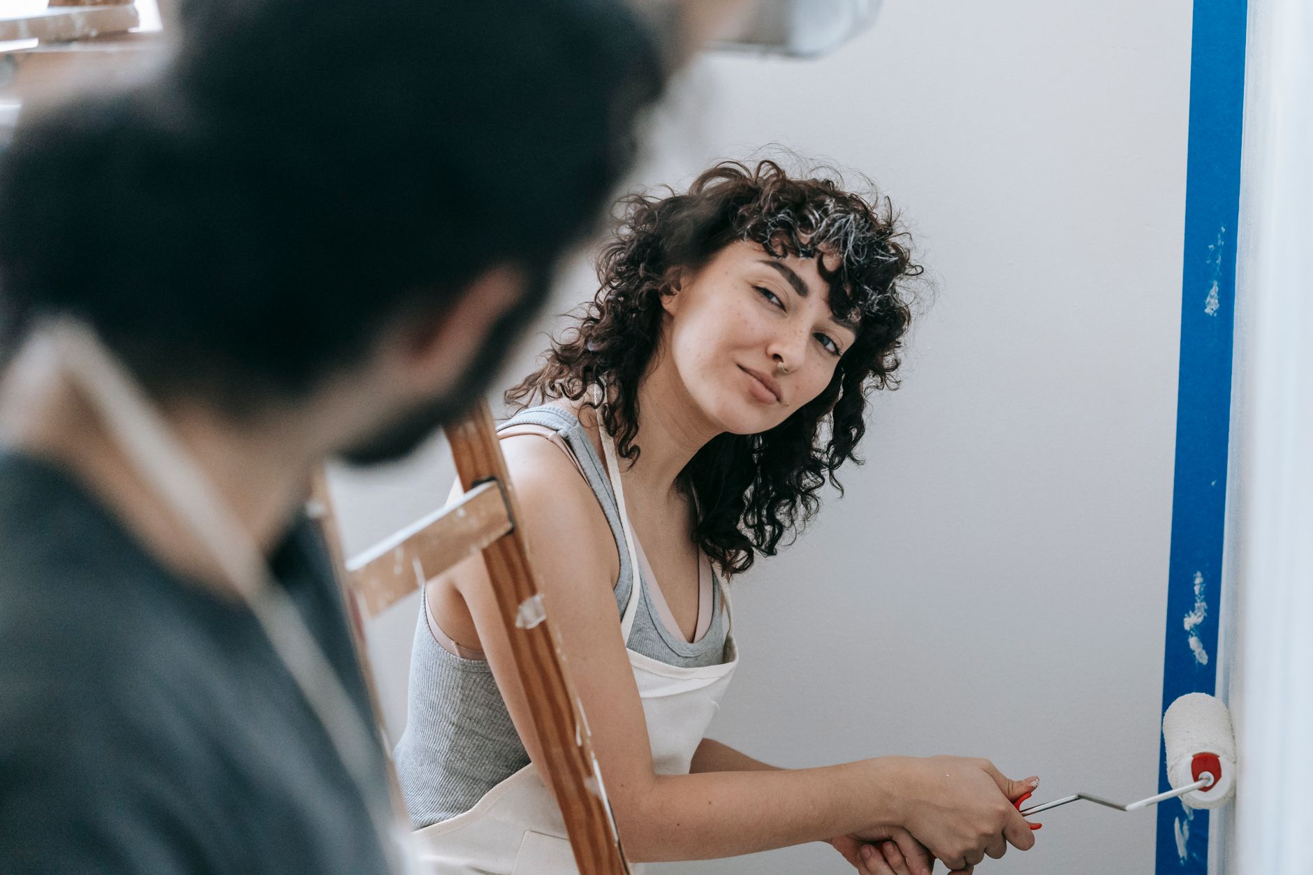 A worker rolling fresh paint onto an interior wall during a unit make-ready