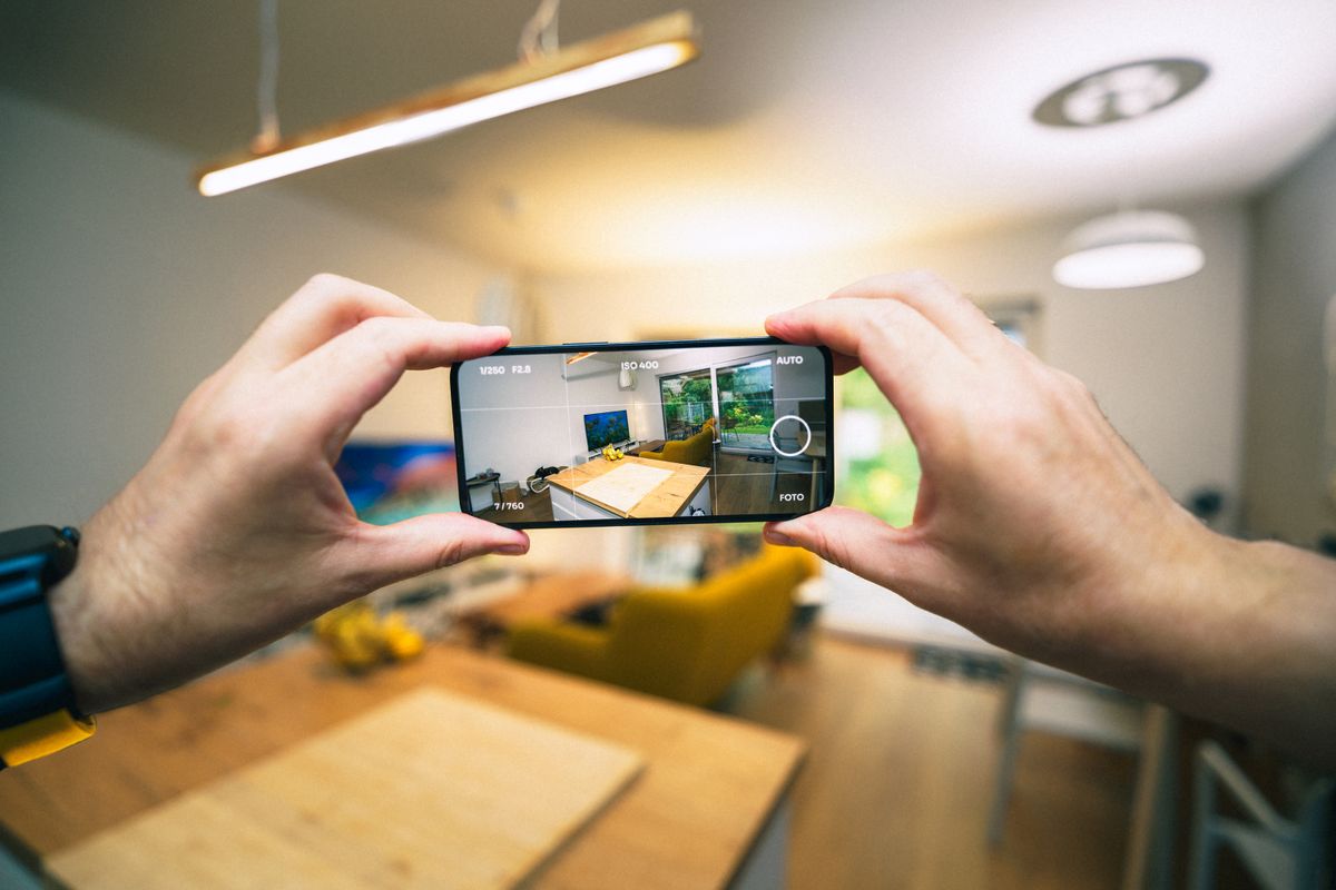 A hand holding a phone, photographing the interior of a rental unit to document its condition.