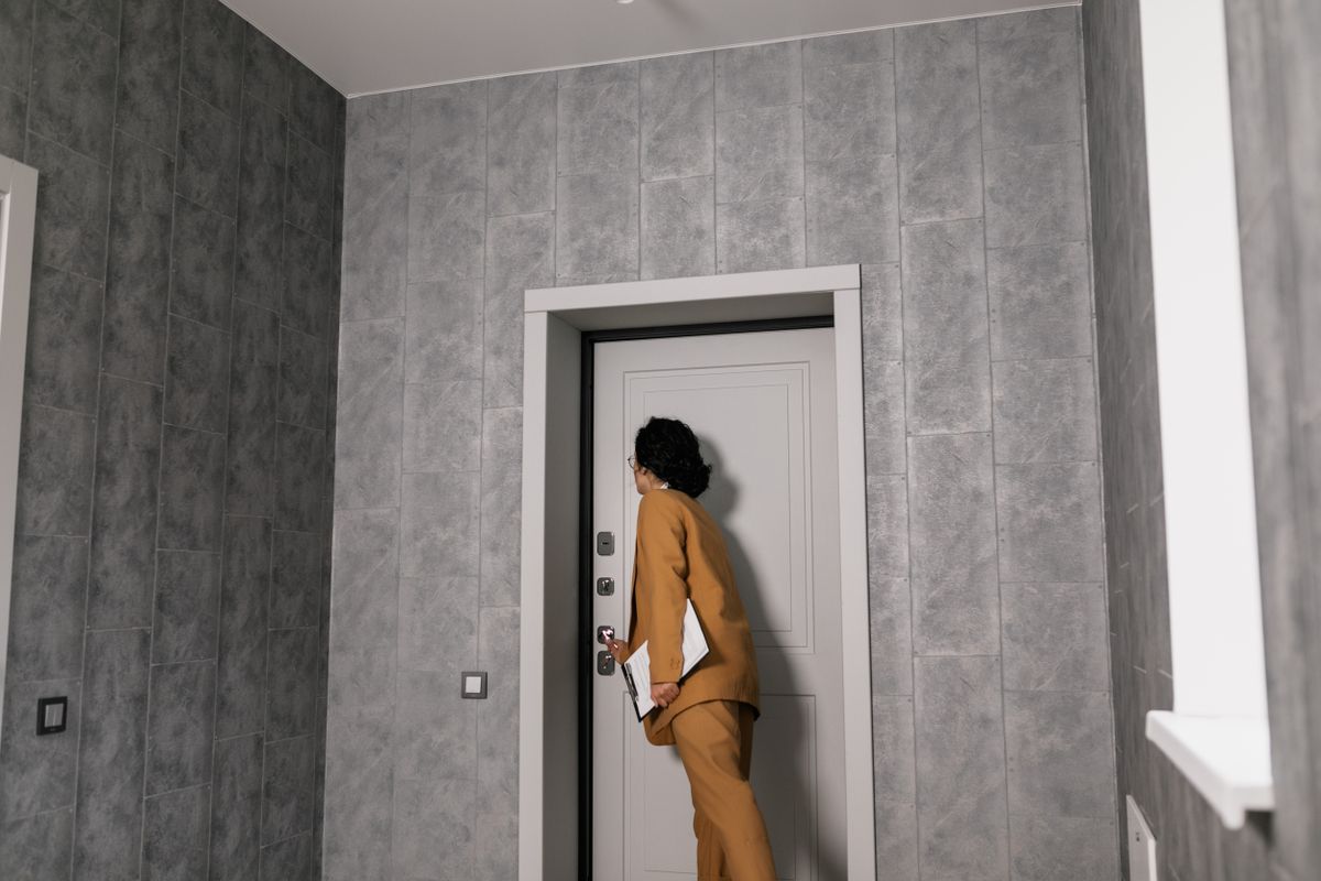 A property manager in business clothes inspecting the entrance of a unit during a walkthrough.