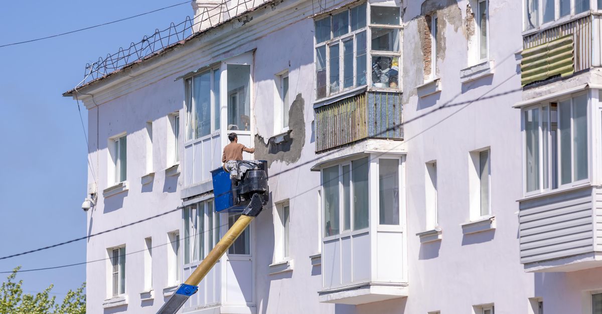 A worker renovating a building facade
