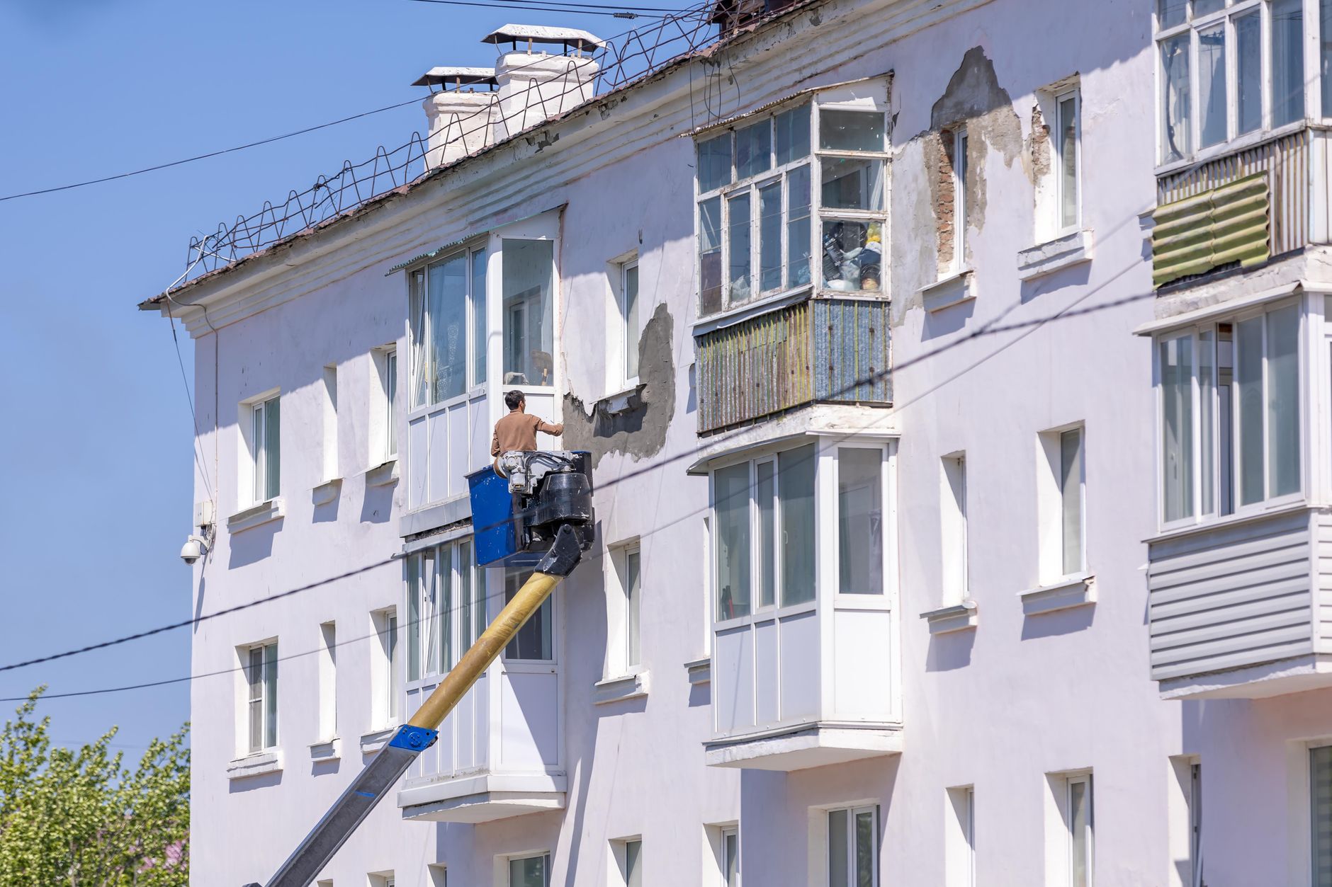 A worker renovating a building facade from a suspended platform